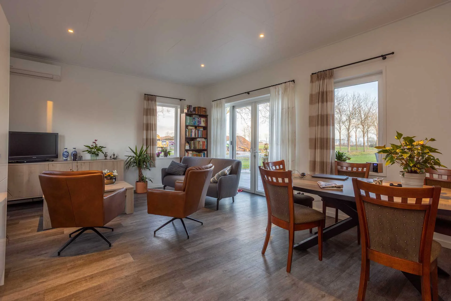 Lichte open woonkamer met brede tuindeuren en een doorlopende houten vloer
