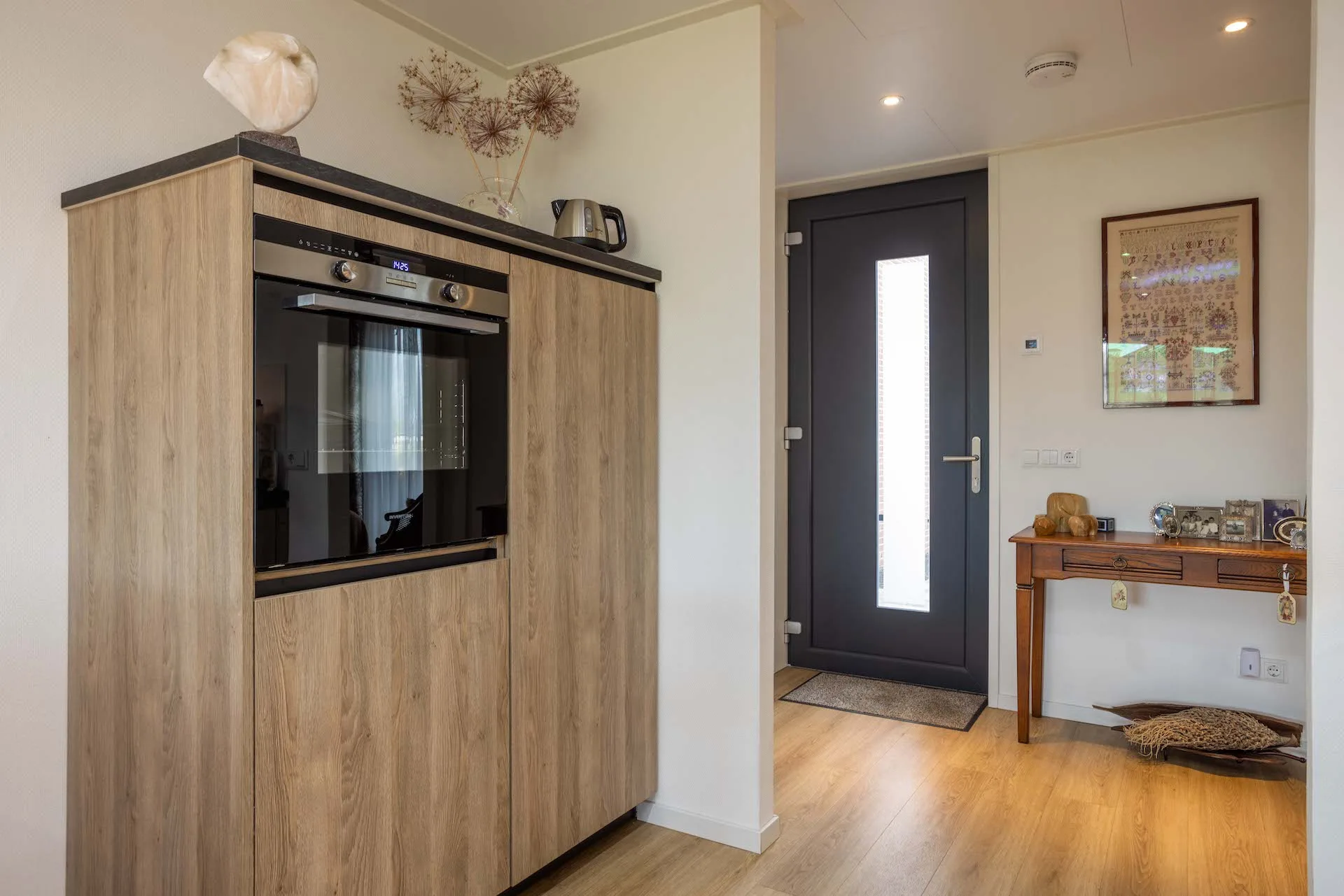 Voordeur met veiligheidsbeslag in een lichte hal van een mantelzorgwoning